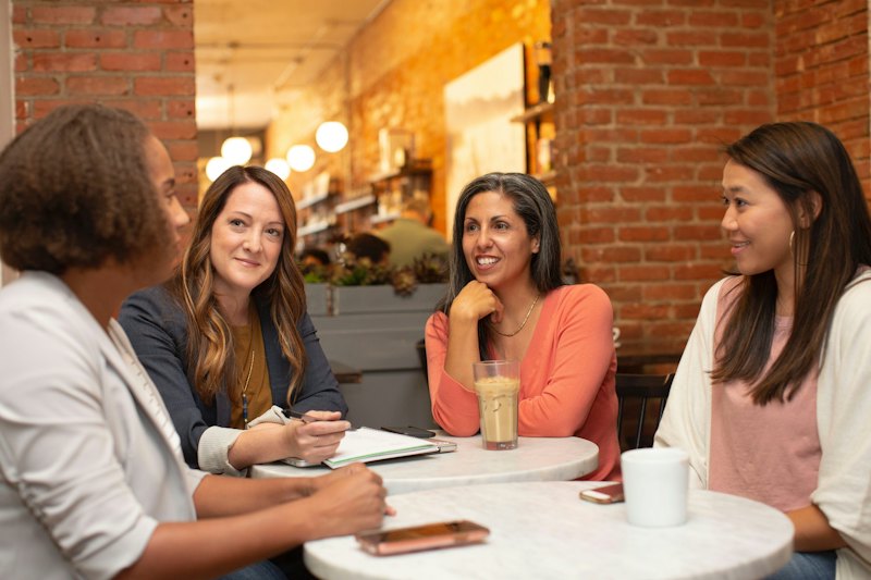 Four women talking around a cafe table